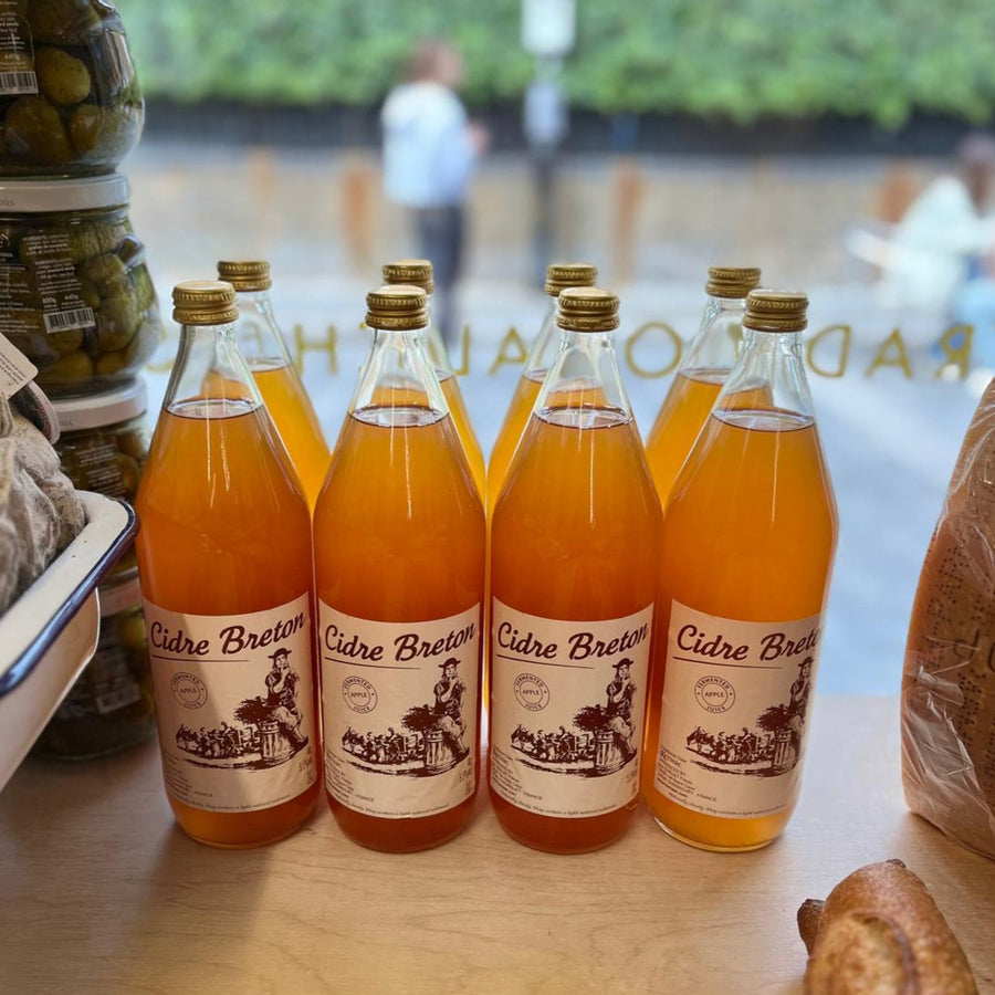 Bottles of Cidre Breton cider on a table in a shop window.