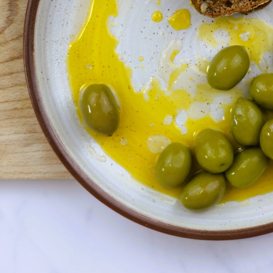 A plate of green olives with olive oil.