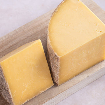 Large cuts of Hafod Cheddar on a wooden board.